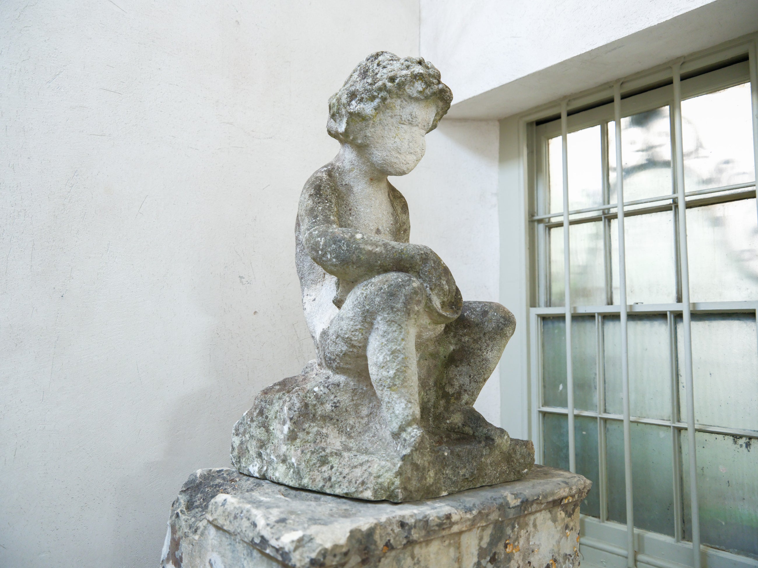 An 18th Century Limestone Putti on a Caen Stone Pillar