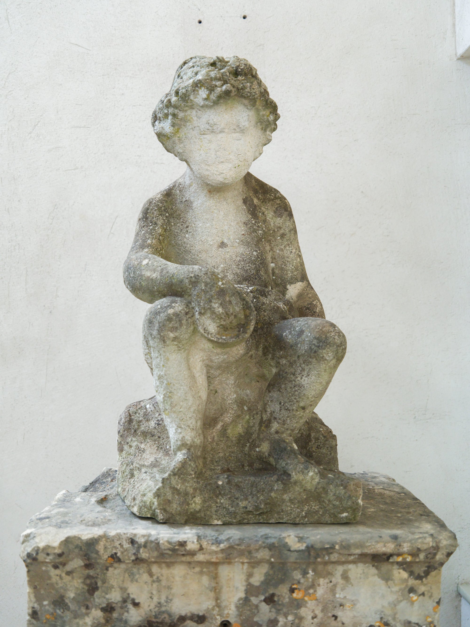 An 18th Century Limestone Putti on a Caen Stone Pillar